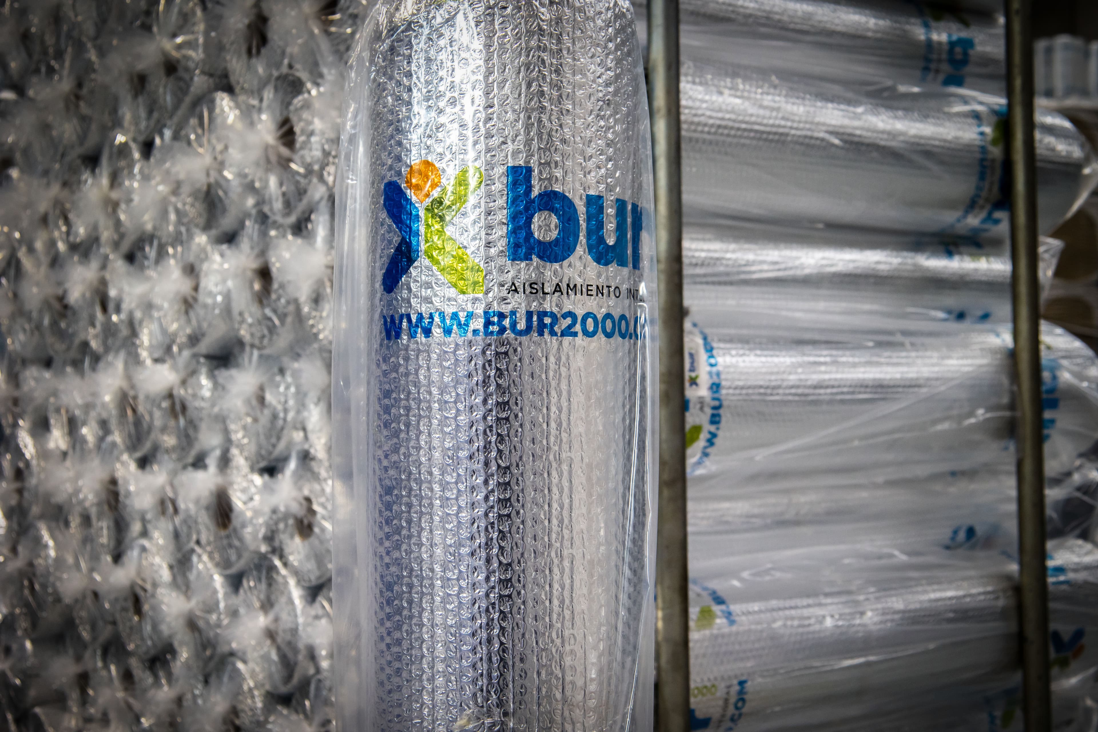 Silver reflective bubble wrap insulation roll with Xbur logo, stored in a large warehouse.